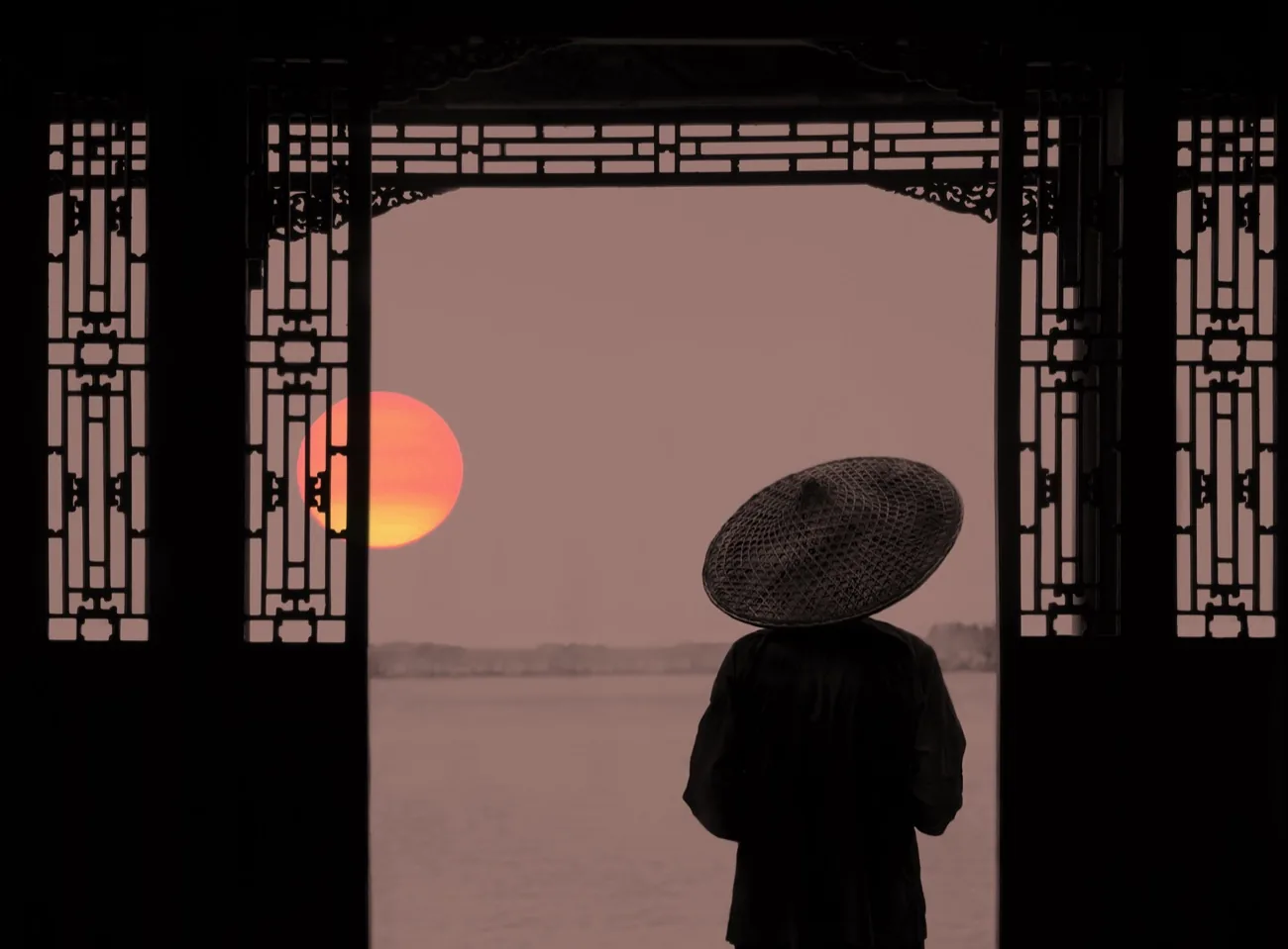 Silhouette au chapeau conique face au coucher de soleil, Chine
